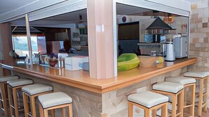 A bar area with a counter, stools, and a view of the kitchen in the background. - Lotus Studios (Hersonissos)