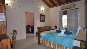 Une chambre à coucher avec un lit, des meubles en bois, une fenêtre avec des rideaux et un climatiseur fixé au mur.