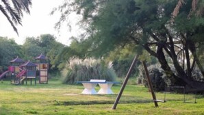 A playground with a slide and climbing structures, surrounded by grass and trees. - Residence La Vallicella (Poggio-Mezzana)