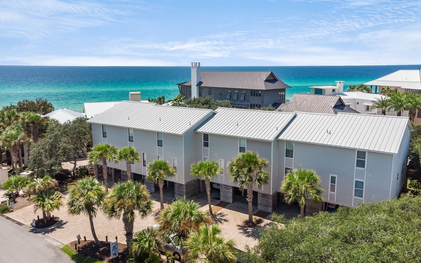 A modern building with a flat roof, located near a beach with clear blue water.