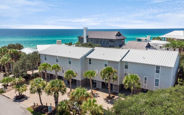 A modern building with a flat roof, located near a beach with clear blue water.