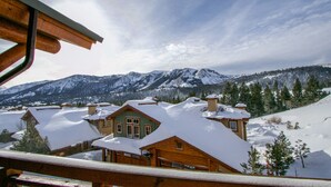 Eine Holzhütte mit schneebedecktem Dach, umgeben von Bergen und Bäumen.