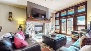 Ein gemütliches Wohnzimmer mit Kamin aus Stein, Ledersofas und einem großen Fernseher.