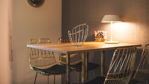 Una mesa de comedor con una silla de alambre metálico, un cuenco de vidrio transparente y una lámpara.