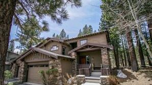 A two-story house with a stone facade, a front porch, and a garage. - Pet-Friendly, Stunning! On Golf Course! Private Hot Tub, Grill, Washer/Dryer (Mammoth Lakes)