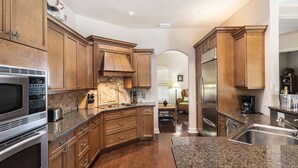 Eine geräumige Küche mit Holzschränken, Granit-Arbeitsplatten, Edelstahlgeräten und einem Essbereich mit Tisch und Stühlen.