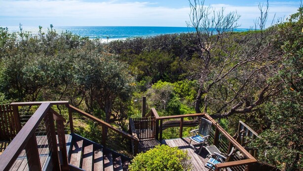 A wooden deck with a view of the ocean and surrounding vegetation. - Illaroo - Absolute Beachfront with Spa (Culburra Beach)