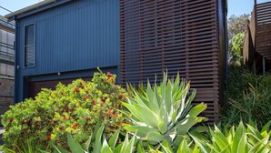 A modern building with a blue exterior and a wooden slatted wall. - Illaroo - Absolute Beachfront with Spa (Culburra Beach)