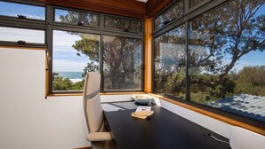 A room with a large window overlooking a scenic view of trees and the ocean. - Illaroo - Absolute Beachfront with Spa (Culburra Beach)