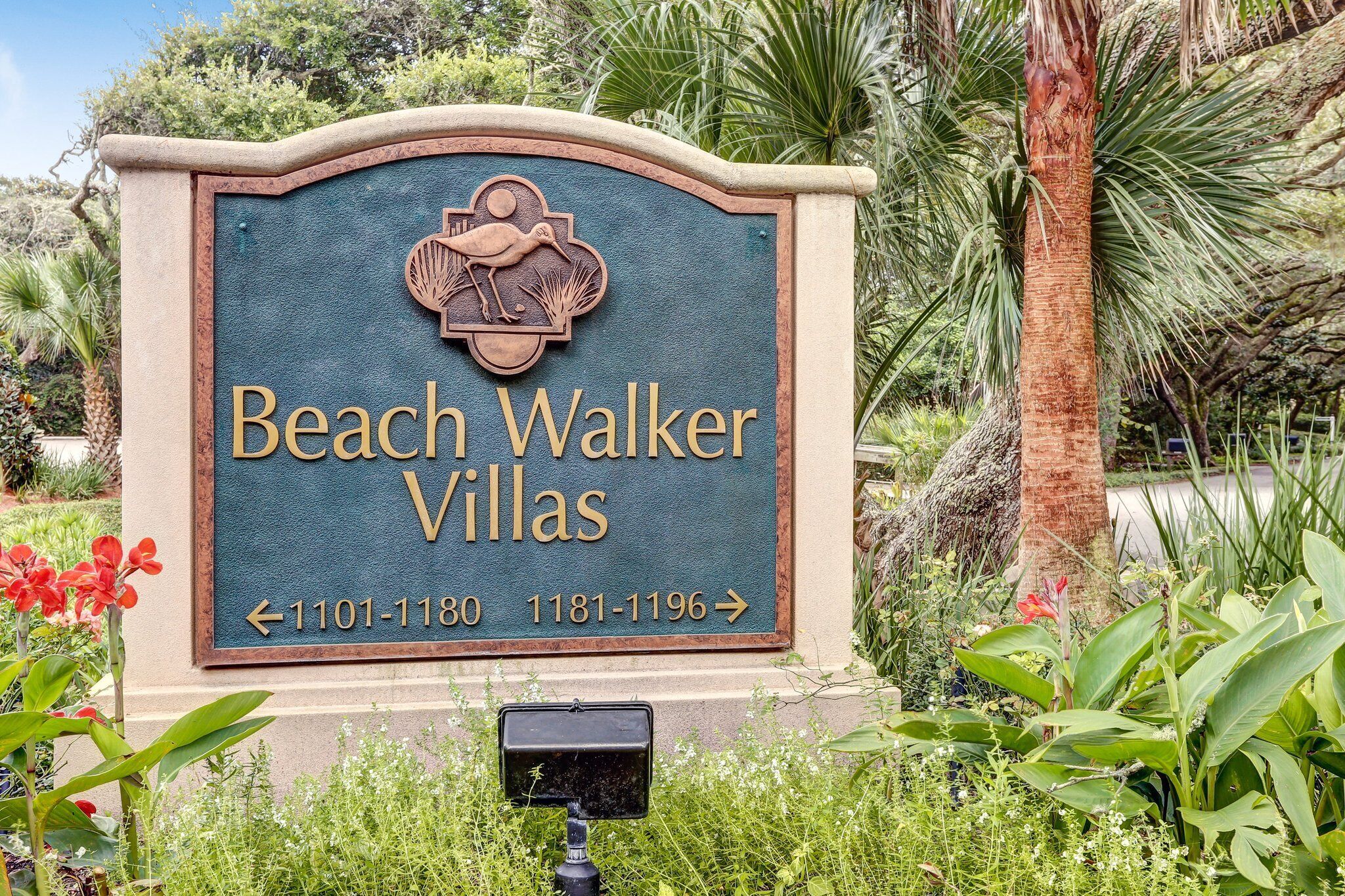 A sign for Beach Walker Villas with directional arrows and phone numbers.