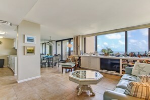 Enjoy ocean views from the large window in this living area, featuring a modern kitchen, dining space, and cozy seating area.