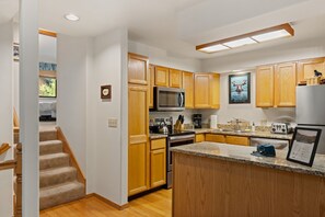 A modern kitchen with wooden cabinets, a stainless steel refrigerator, a microwave, and a granite countertop. - Outpost: Clark's Knoll 367 - Walk to Town Square (Jackson)