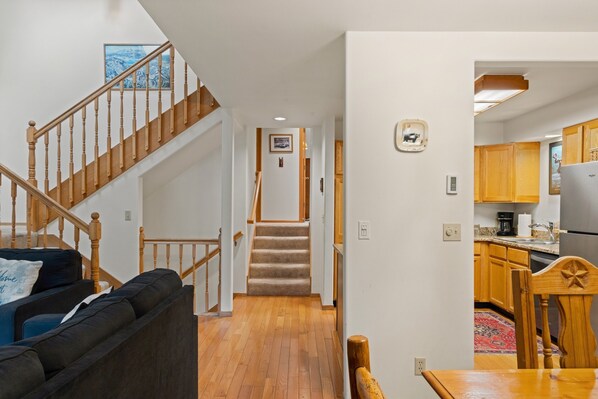 A home interior with a staircase leading to a bedroom, a living room with a sofa, and a kitchen area.