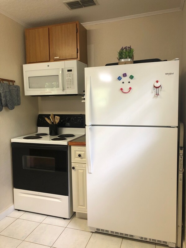 A kitchen with a white refrigerator, a microwave, a stove, and wooden cabinets. - Suwannee River Retreat with Private Dock, Free Kayaks, and Fire pit (Mayo)