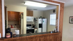 A kitchen with wooden cabinets, a microwave, a refrigerator, and a stove.