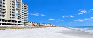 A beachfront hotel with multiple floors, a sandy beach, and a clear blue sky. - One Ocean Place 509 - Oceanfront in Garden City Beach (Garden City)