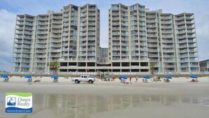 Een hoog hotel met diverse balkons en een ligging aan het strand.