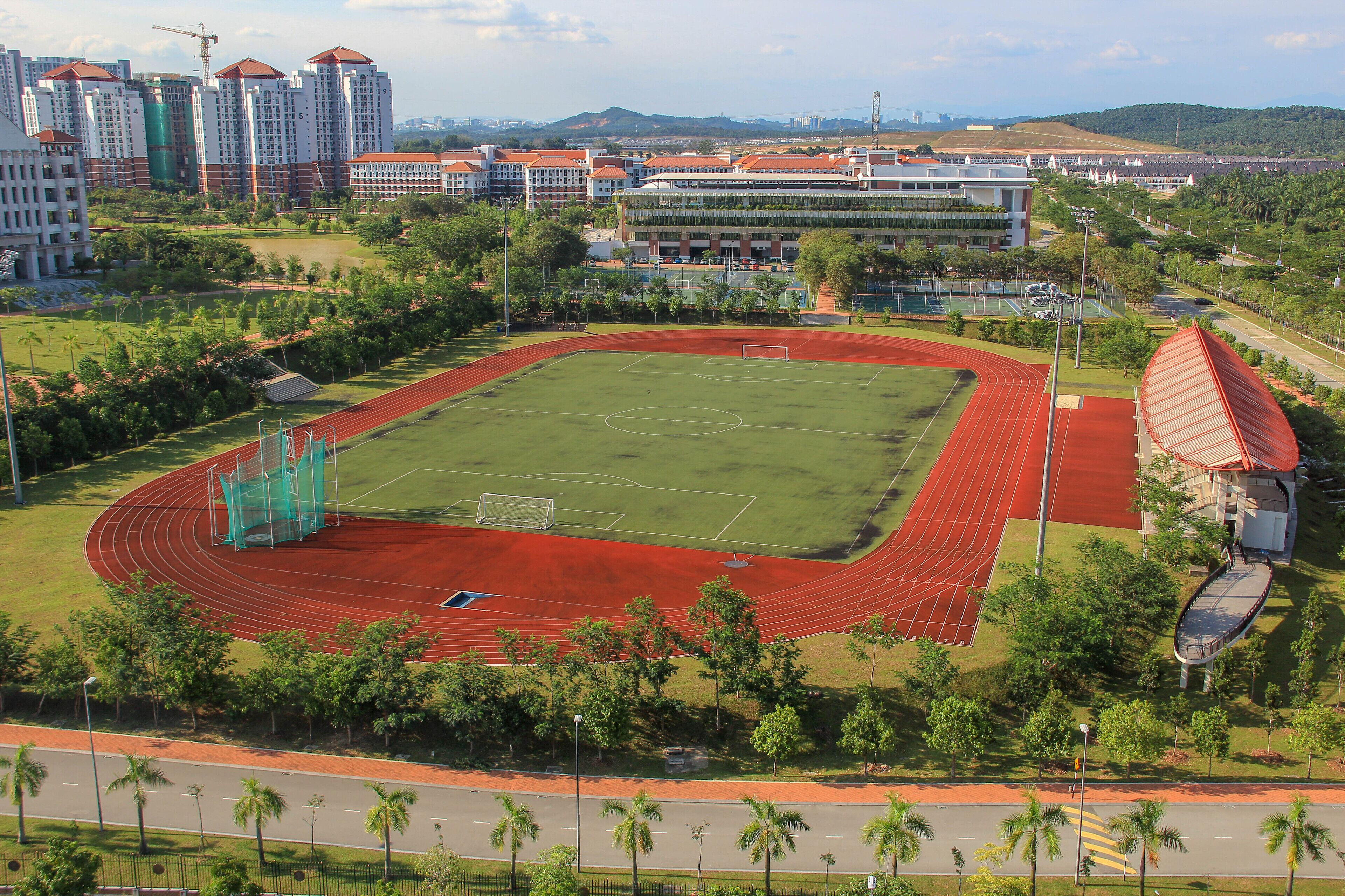 A large sports complex with a running track, a football field, and a tennis court.