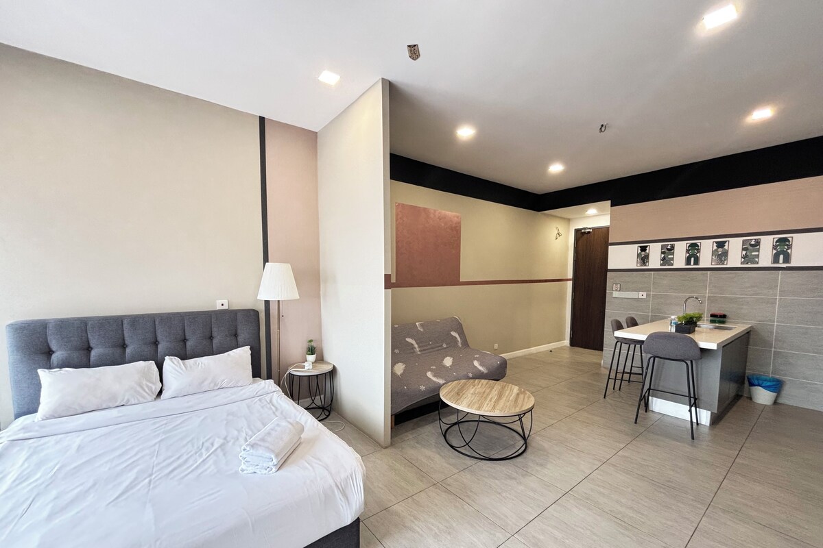 A modern hotel room with a bed, bedside table, lamp, and a small round table.
