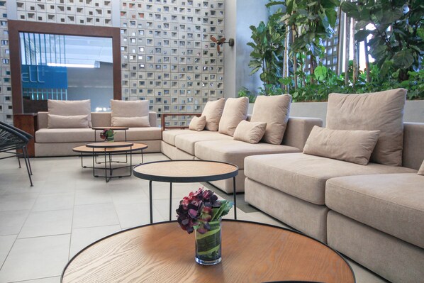 Una sala de estar moderna con un sofá color beige, una mesa de centro y un jarrón decorativo con flores.