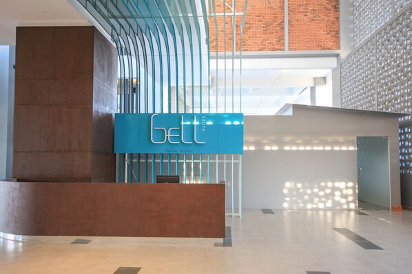 A modern hotel reception area with a prominent blue sign indicating 'Sunsuria City Suites'. - Bell Suites by Salaam Suites (Sepang)