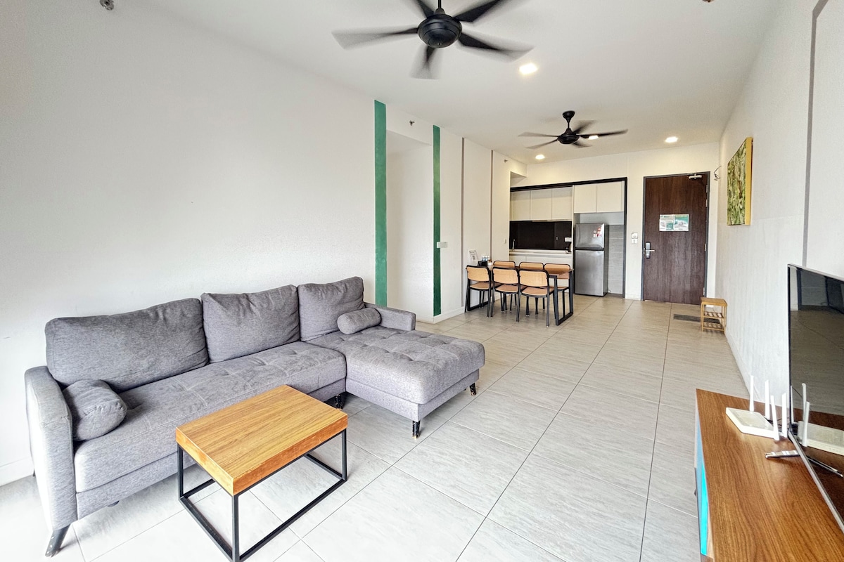 A modern living room with a grey sectional sofa, a wooden coffee table, and a dining area with a table and chairs.