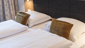 Habitación de hotel con dos camas, cada una con sábanas blancas y cabeceros oscuros.
