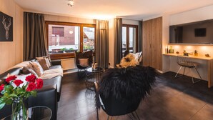 Una sala moderna con un sofá, un comedor con televisor y vistas al exterior.