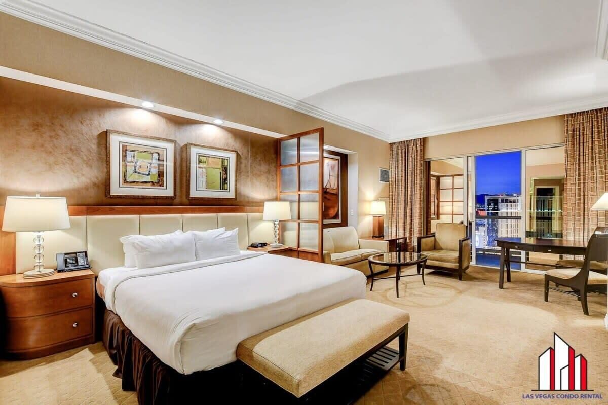 Een hotelkamer met een groot bed, een bureau, een stoel en uitzicht op de stad.