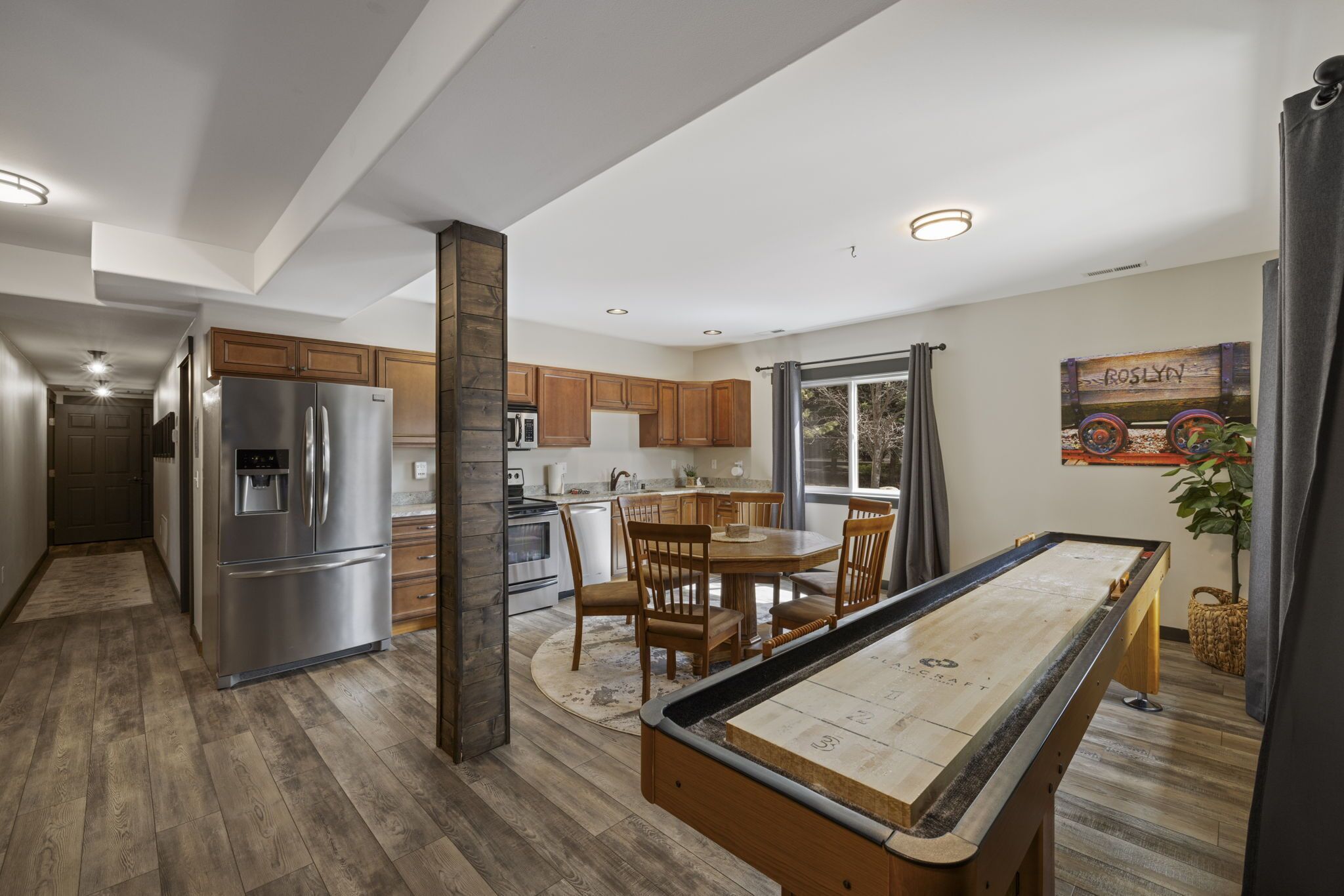 A modern kitchen with wooden cabinets, stainless steel appliances, and a pool table.