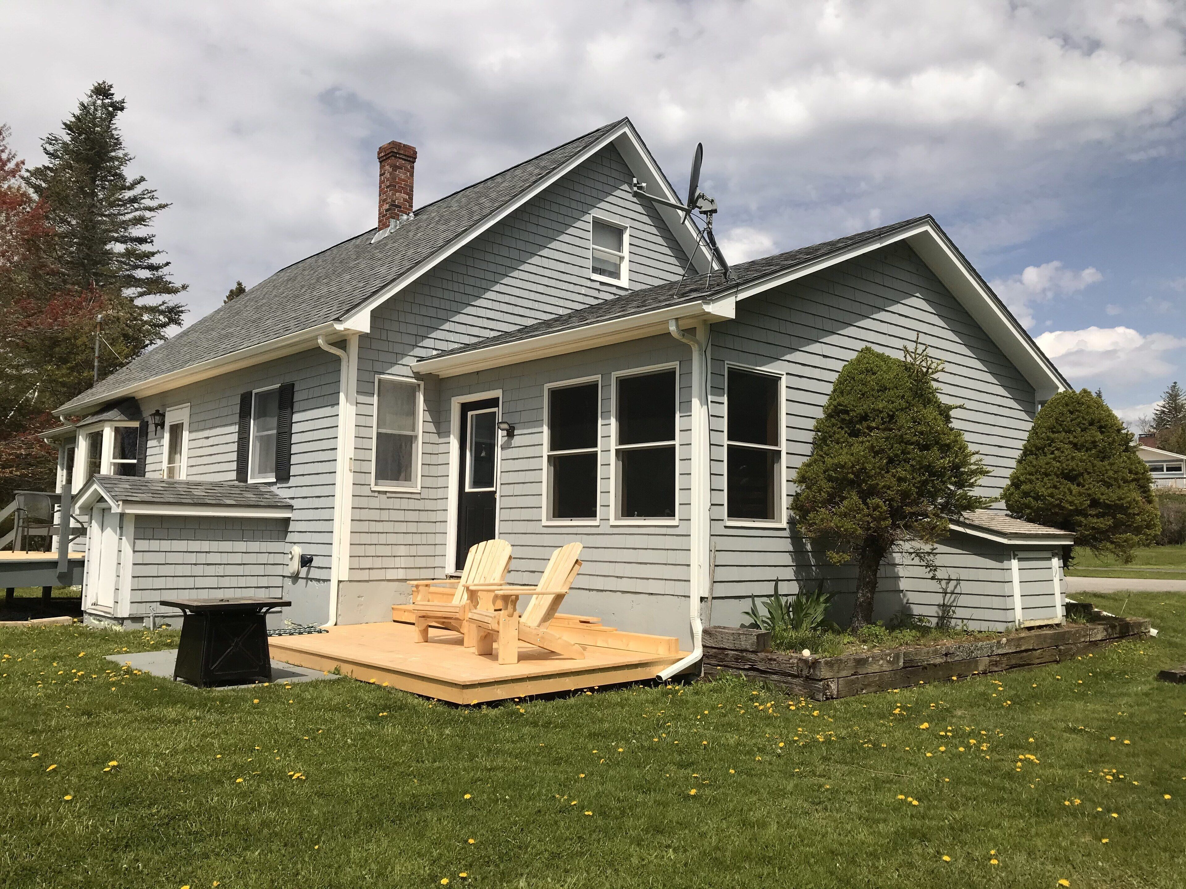 A house with a covered porch, a chimney, and a satellite dish.
