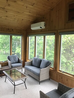 Une pièce chaleureuse, meublée de meubles en osier, dotée de grandes fenêtres et d’un ventilateur de plafond.
