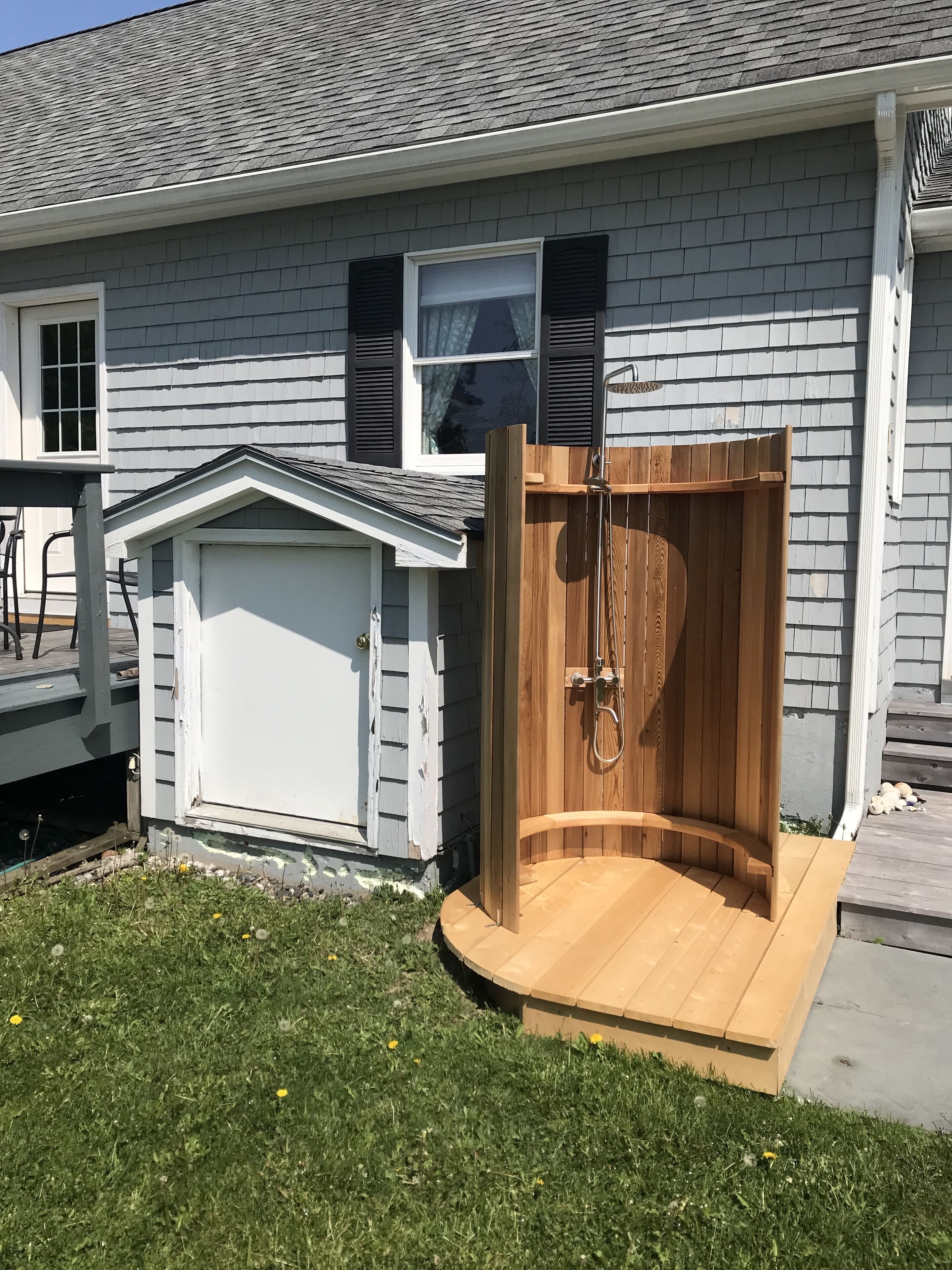 A house with a wooden deck, a garage, and a wooden door leading to a covered outdoor area.