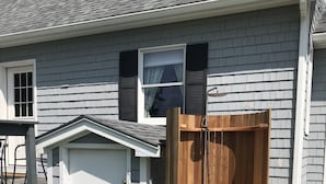 A house with a wooden deck, a garage, and a wooden door leading to a covered outdoor area.