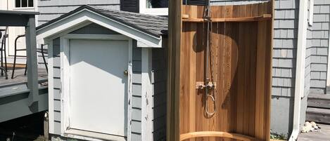A house with a wooden deck, a garage, and a wooden door leading to a covered outdoor area.