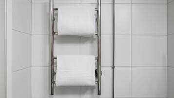 Un baño con un perchero que sostiene dos toallas blancas.