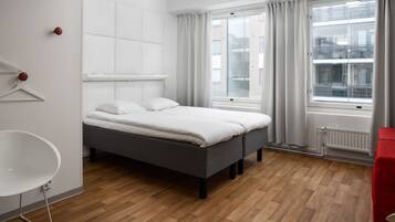 A modern bedroom with a grey bed, white walls, and a wooden floor.
