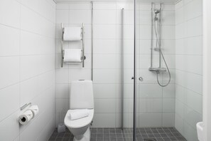Un baño moderno con inodoro, ducha y cabina de ducha con paredes de vidrio.