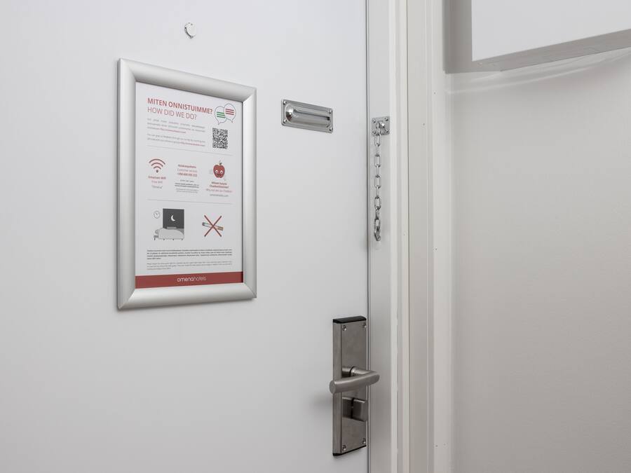 Eine weiße Tür mit einem Hinweisschild, einem Metallgriff und einem Kettenvorhang.