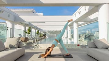 Un espacio interior moderno con una colchoneta de yoga, un sofá y una zona de piscina.