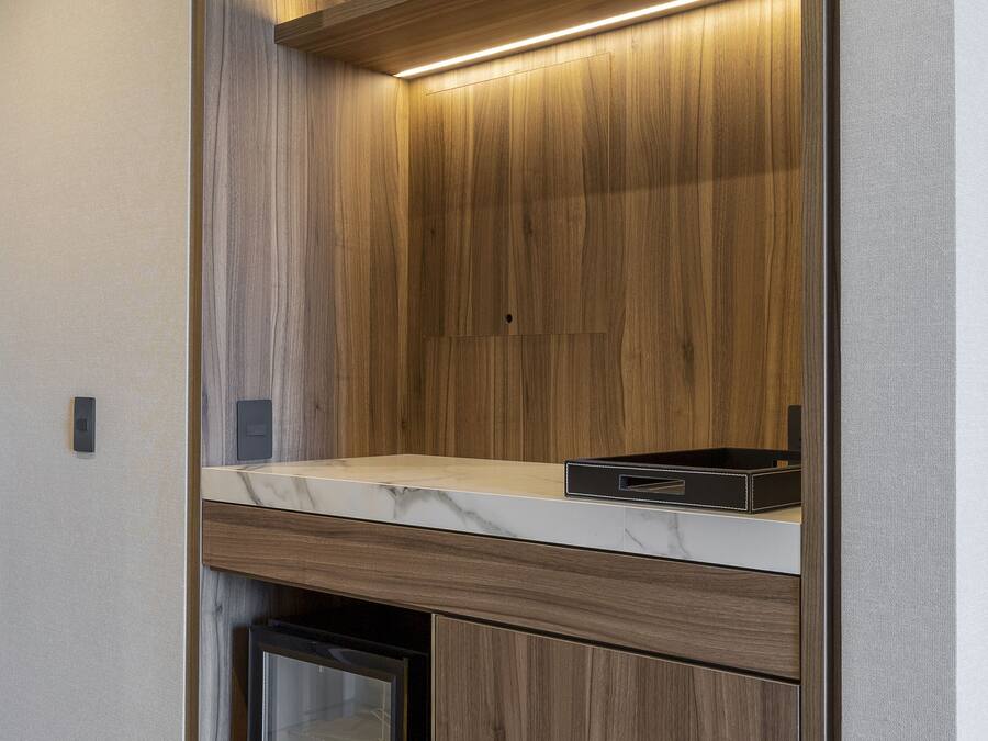 A modern kitchen with wooden cabinetry, a marble countertop, and built-in appliances.