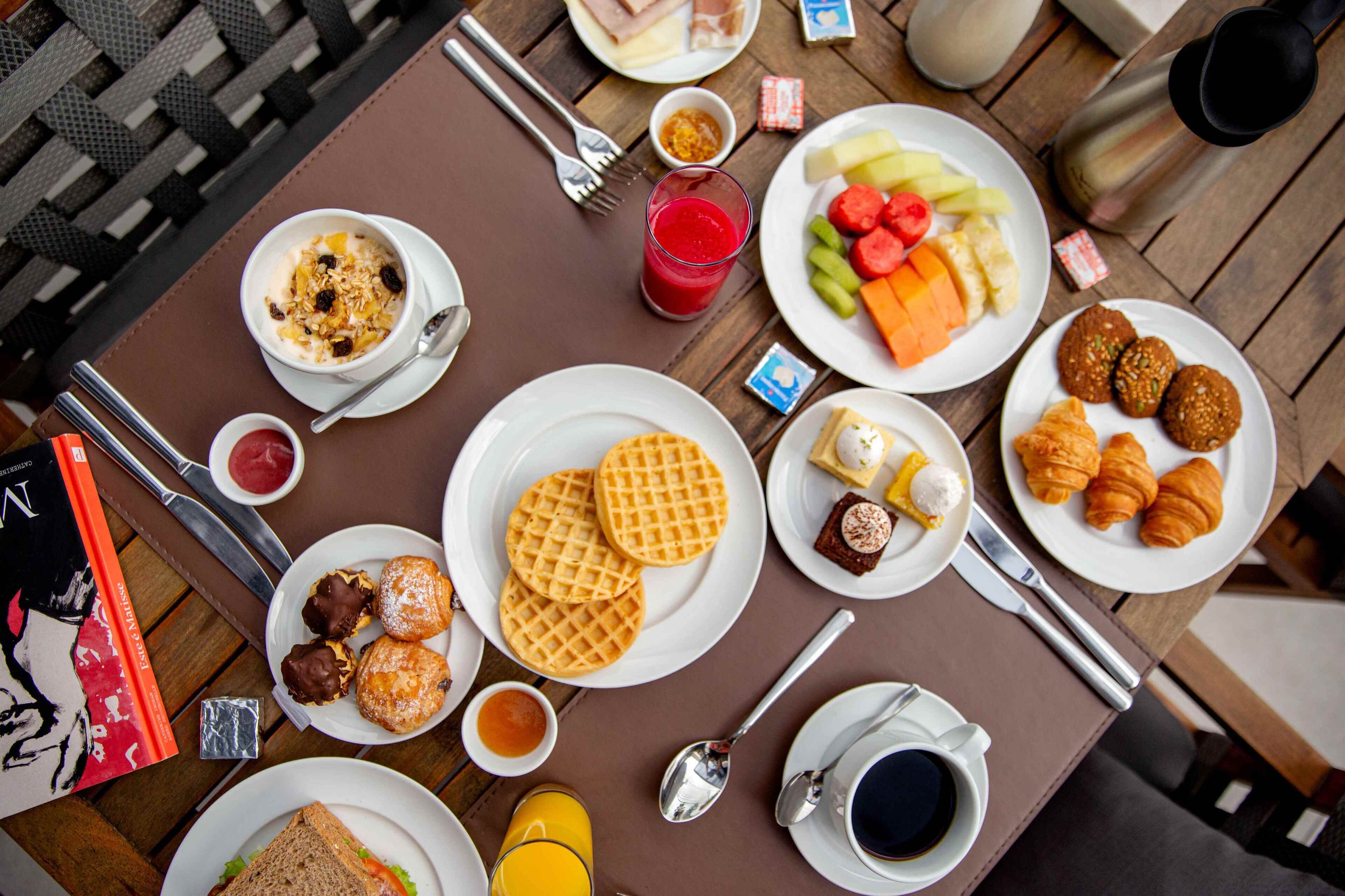 Et morgenbord med vafler, croissanter samt forskellige frugter og kager.