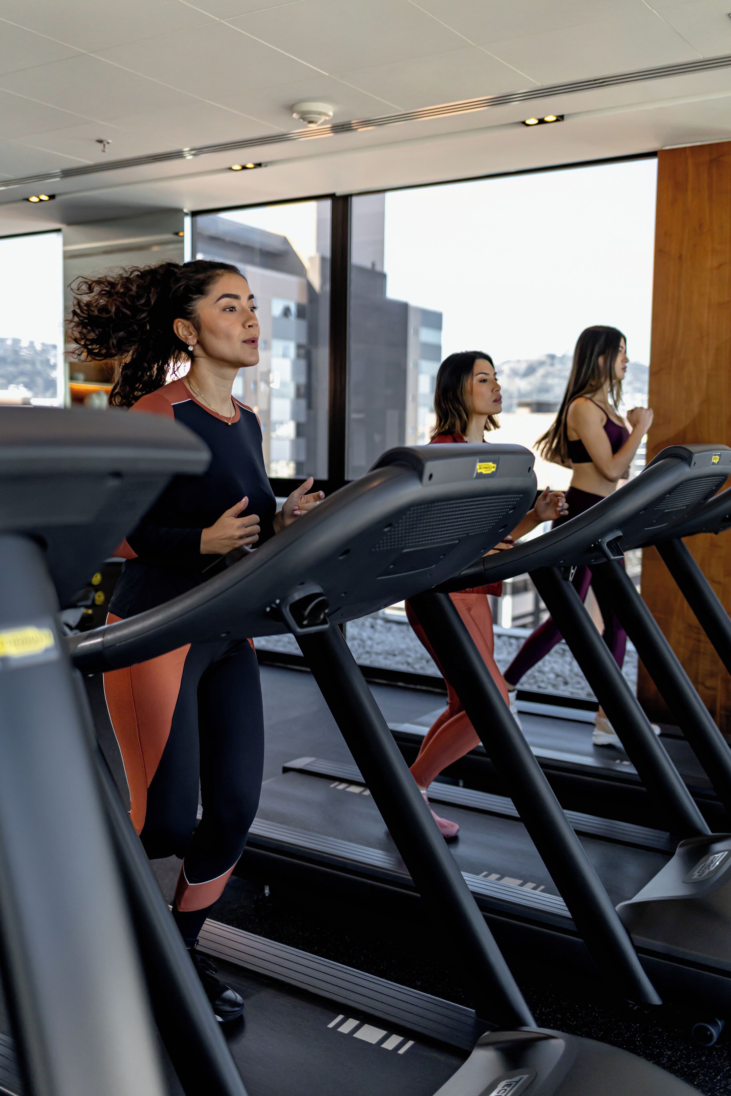 Une salle de sport équipée de tapis de course et offrant une vue sur la ville.