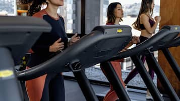 Une salle de sport équipée de tapis de course et offrant une vue sur la ville.