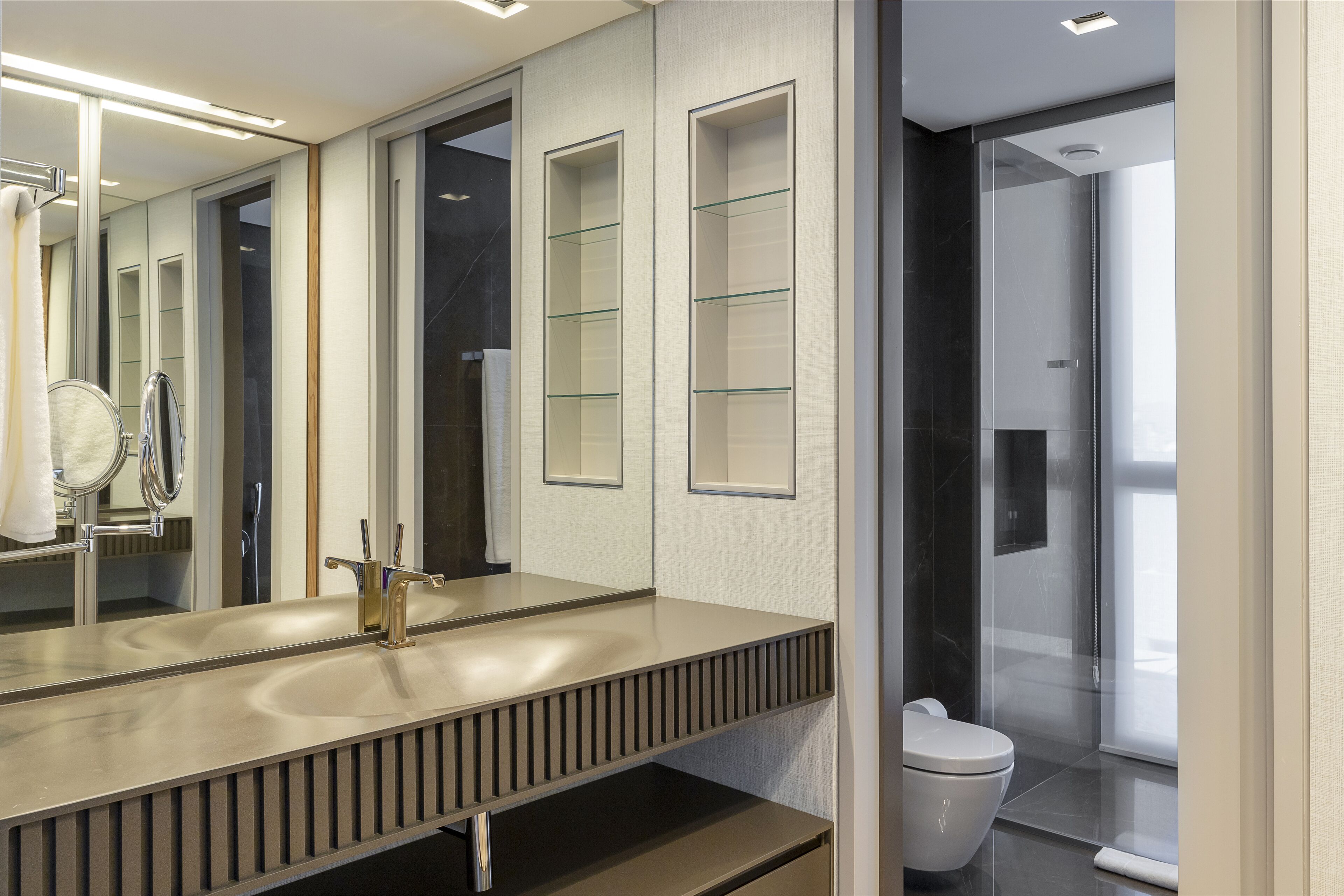 Ein modernes Badezimmer mit großem Spiegel, Waschbecken und Toilette.