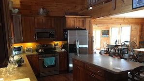 Cocina estilo cabaña de madera con isla central, microondas integrado, refrigerador y estufa.