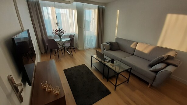 A modern living room with a sofa, coffee table, and dining area. - Apartament plaża 41 bros (Gdansk)