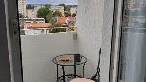 A balcony with a table and chair, a small plate of cookies, and a cup. - Apartament plaża 41 bros (Gdansk)