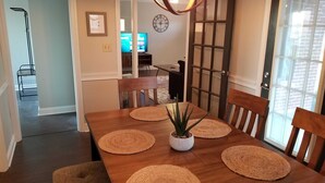 A dining area with a wooden table, four chairs, and woven placemats. - Clean & Safe in Downtown Morristown (Morristown)