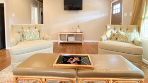 Ein Wohnzimmer mit zwei Sofas, einem Couchtisch und einem an der Wand befestigten Fernseher.